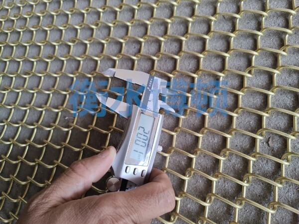 正在使用卡尺检测铜合金网的网孔尺寸, 显示为20mm.