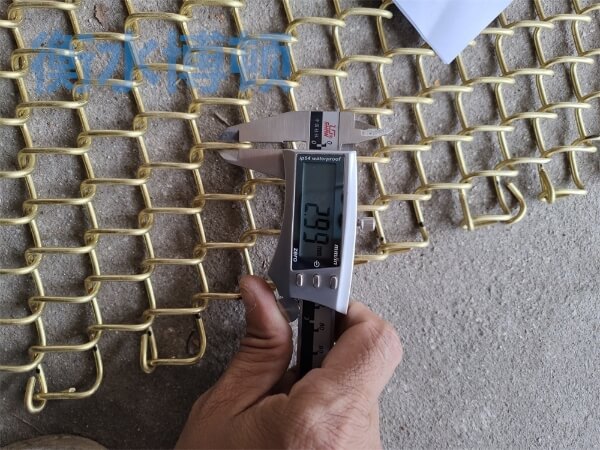 正在使用卡尺检测铜合金网的网孔尺寸, 显示为2.99mm.